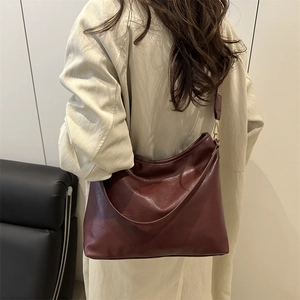 Sac fourre-tout chic en cuir bordeaux sur mannequin en trench-coat beige