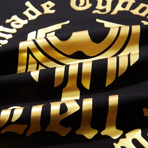 Oversized black cotton T-shirt featuring gold foil gothic prints and textured streetwear style