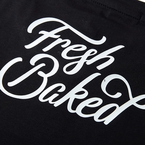 Black cotton t-shirt featuring rainbow reflective Fresh Baked script printing detail