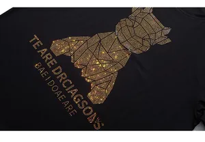 Detail of a black T-shirt showing a 3D geometric bear design with golden rhinestones