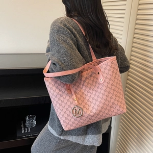 Pink monogram tote bag with metallic charm shown on model in a minimalist home setting