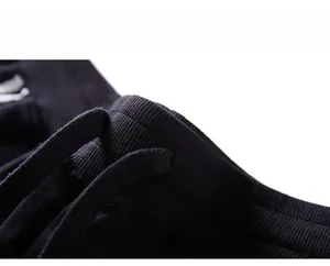 Detail of the elastic ribbed waistband with matching drawstring on black knit shorts