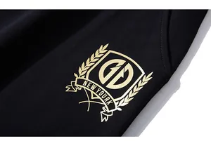Détail du short noir avec un blason doré, des lettres GD et une couronne de lauriers