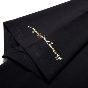 Black cotton t-shirt sleeve cuff detail featuring a golden 'Enjoy your journey' print