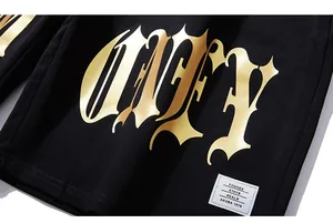 Detail of black cotton shorts with golden gothic print and white woven label