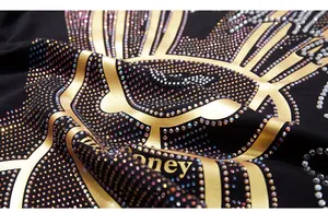 Detailed macro of gold foil bunny print and colorful rhinestones on black knit fabric