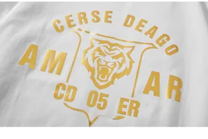 Detailed close-up of golden metallic tiger print and lettering on a white cotton T-shirt