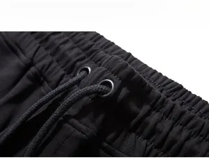 Detailed macro view of black joggers' elastic waistband with metal eyelets and drawstrings