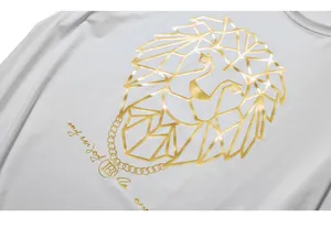 Close-up of golden lion print and metallic branding logo on white cotton T-shirt