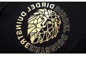 Detailed close-up of golden geometric lion print on black oversized cotton t-shirt