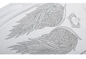Detail of the sparkling rhinestone wing and crown pattern on a white cotton t-shirt