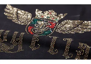 Macro view of rhinestone crown and wings design on premium black knitted fabric