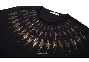 Close-up of golden lightning bolt rhinestone pattern on black T-shirt neckline