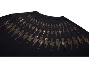 Detail of multi-row gold lightning bolt rhinestone design on a black cotton tee neck
