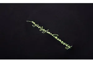 Macro shot of 3D neon green embroidery on premium black knit cotton t-shirt fabric
