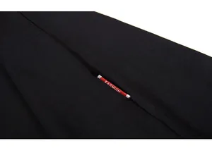 Detailed close-up of a red woven label with white FASHION text on a black knit shirt