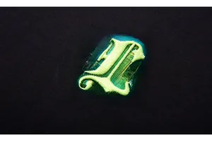 Macro shot of neon green gothic embroidery on black premium cotton t-shirt fabric