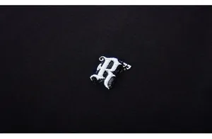 Close-up of premium white gothic letter R embroidery on a black knit cotton T-shirt