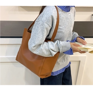 Vista laterale della borsa tote grande marrone in ecopelle sul modello mostra misura