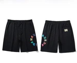 Detail view of black oversized shorts with drawstring waist and colorful graphic prints