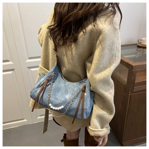 Détail du sac hobo en denim bleu avec chaîne en perles et détails métalliques chics