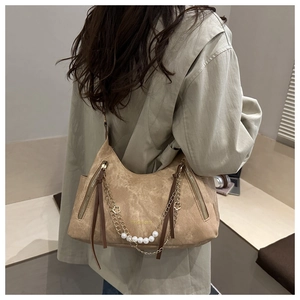 Détail du sac bandoulière en daim marron avec chaîne dorée, perles et franges en cuir