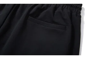 Close-up of elastic waistband and rear pocket with yellow a6 graphic on black knit pants