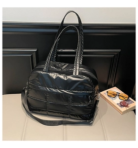 Gros plan sur le sac fourre-tout en nylon noir matelassé avec bandoulière réglable