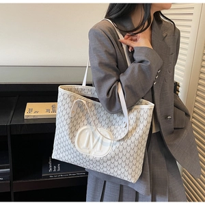 Detail of white tote bag with grey M pattern and circular logo in a minimalist setting