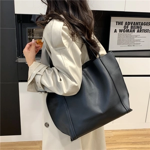 Elegante borsa tote nera in pelle opaca di grande capacità indossata da una modella