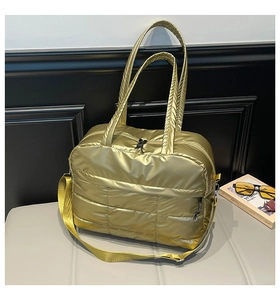 Détail du sac fourre-tout matelassé doré avec texture brillante et poignées rembourrées