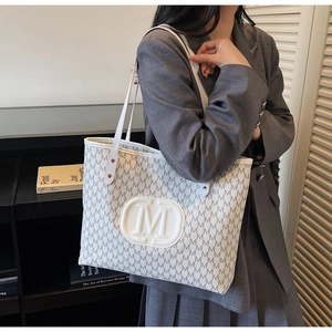 Detailed side view of a large white tote bag with grey M letter patterns and a round logo