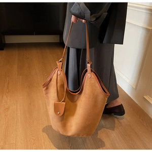 Detail of a large brown suede tote bag featuring a matching small coin purse and metal snap
