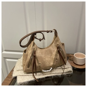Détail du sac à bandoulière en daim kaki avec chaîne perlée et fermeture à glissière à pompon