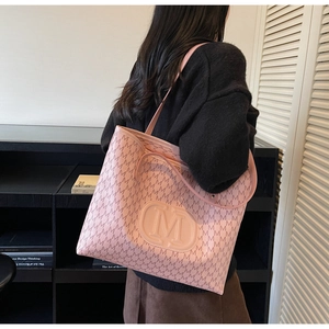 Side view of a large pink tote bag with letter M prints and embossed logo on model
