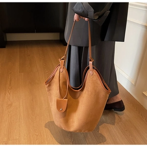 Detail of caramel suede tote bag with stylish round hanging charm shown in interior