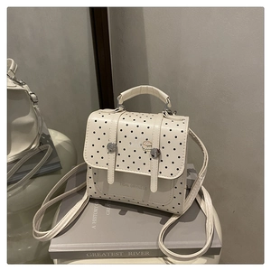 Polka dot white backpack on a white stool with a hamburger graphic and flap closure