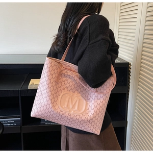 Detail of pink tote bag featuring embossed M logo and stylish monogram pattern for women