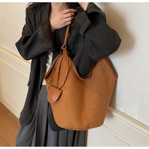 Detail of soft brown suede tote bag with round leather charm and smooth texture