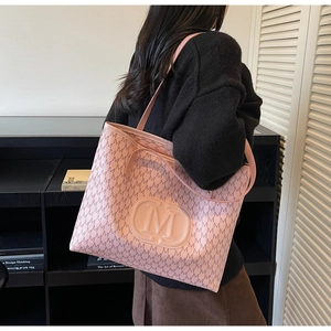 Detail of light pink tote bag with M-pattern print and embossed logo on model