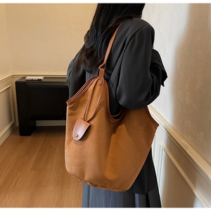 Side view of large brown suede tote bag with drawstring closure worn by model