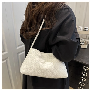 Dettaglio della borsa hobo bianca in pelle intrecciata portata a spalla su abiti neri
