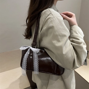 Borsa sottobraccio marrone in similpelle con fiocco in pizzo bianco indossata dal modello