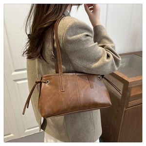 Detail of vintage brown leather tote bag with side ribbons and shoulder straps