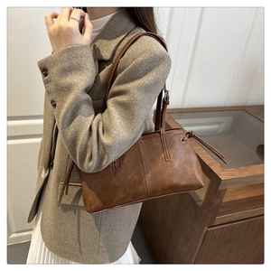 Brown leather tote bag featuring a minimalist design and knotted strap detail on the side