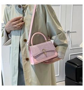 Détail de sac à main rose pailleté avec fermoir fer à cheval doré et texture en cuir PU