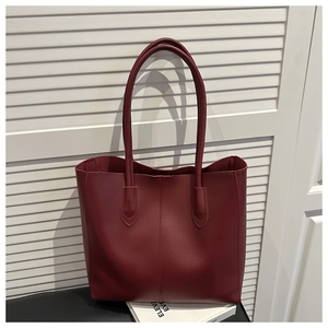 Detail of burgundy tote bag with vertical stitching on a black chair against white blinds