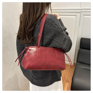 Detail of red vintage matte leather tote bag with side drawstring and shoulder strap