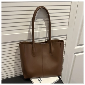 Detail of minimalist dark brown leather tote bag with vertical stitching on white background