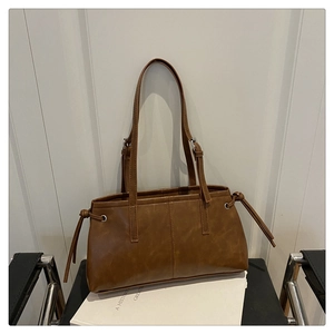 Detail view of brown tote bag showing side drawstring knots and adjustable shoulder straps